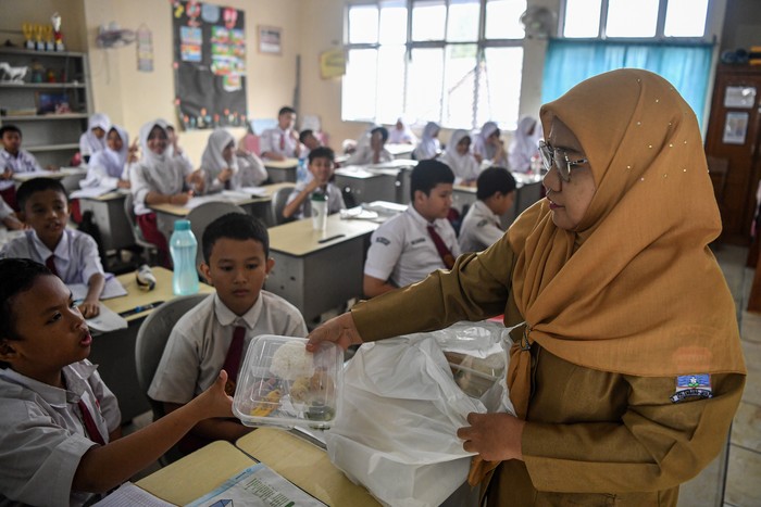 Guru membagikan paket makan siang kepada siswa dalam pelaksanaan Program Makan Bergizi Gratis (MBG) di SD Negeri 25 Palembang, Sumatera Selatan, Senin (6/1/2025).   Pelaksanaan perdana Program Makan Bergizi Gratis (MBG) di Kota Palembang tersebut baru dilaksanakan di lima sekolah yang berada dilingkungan Kecamatan Ilir Barat (IB) 1, Palembang  yaitu TK Panca Bakti, SDN 24, SDN 25, SMPN 19 dan SMPN 33 dengan total siswa sebanyak 2.968 siswa. ANTARA FOTO/Nova Wahyudi/nz