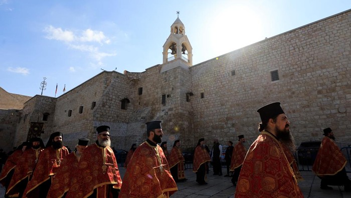 Umat Kristen Orthodoks Rayakan Natal di Betlehem Members of the police stand guard outside the Church of the Nativity on the day of celebrations for Christmas, according to the Eastern Orthodox calendar, in Bethlehem, in the Israeli-occupied West Bank, January 6, 2025. REUTERS/Mussa Qawasma