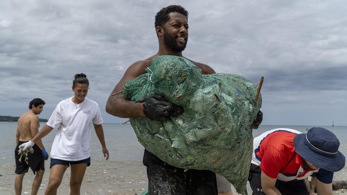 Volunteers load sacks of trash washed ashore by seasonal monsoon tides onto an excavator during a beach clean up at Kedonganan Beach in Badung on the resort island of Bali, Indonesia, Sunday, Jan. 5, 2025. (AP Photo/Dicky Bisinglasi)