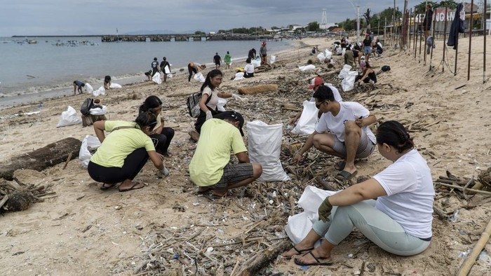 Volunteers load sacks of trash washed ashore by seasonal monsoon tides onto an excavator during a beach clean up at Kedonganan Beach in Badung on the resort island of Bali, Indonesia, Sunday, Jan. 5, 2025. (AP Photo/Dicky Bisinglasi)