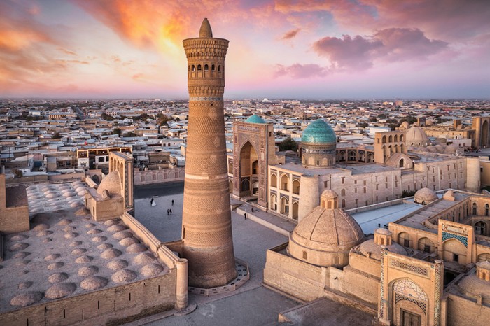 Bukhara Colorful sunset twilight over the famous old town in the City of Bukhara with the iconic Kalyan Minaret and Mir-i-Arab Madressa. Aerial Drone Point of View. Itchan Kala, Bukhara, Khorezm Region, Uzbekistan, Central Asia.