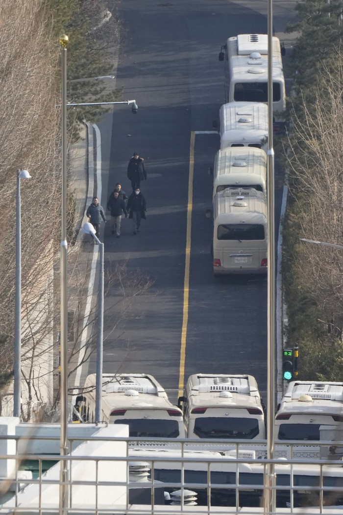 Deretan Bus Halangi Gerbang Masuk Kediaman Presiden Korsel Yoon Suk Yeol Security personnel walk on a road lined up with buses blocking the entrance gate of impeached South Korean president Yoon Suk Yeol's residence in Seoul, South Korea, Wednesday, Jan. 8, 2025. (AP Photo/Ahn Young-joon)
