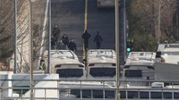 Petugas keamanan berjalan di jalan yang dipenuhi bus yang menghalangi gerbang masuk kediaman mantan presiden Korea Selatan Yoon Suk Yeol di Seoul, Korea Selatan, Rabu (8/1/2024).  