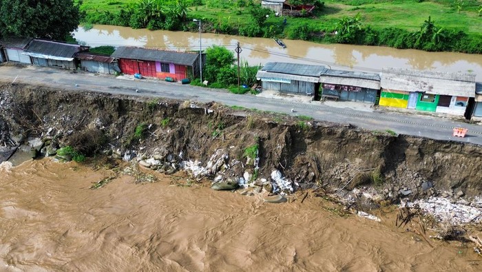 Foto udara jalan Raya Mliriprowo ambrol tergerus air sungai di Bendungan Rolak Songo, Desa Mliriprowo, Tarik, Sidoarjo, Jawa Timur, Selasa (7/1/2025). Intensitas hujan tinggi dalam beberapa hari terakhir membuat debit air Sungai Brantas di pintu dam Rolak Songo mengalami peningkatan, mengakibatkan jalan Raya Mliriprowo ambrol tergerus air sungai. ANTARA FOTO/Umarul Faruq/Spt.