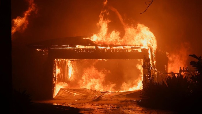 Kebakaran Hutan di California Hangusnya Rumah hingga Restoran Flames rise from a structure as the Eaton Fire burns in Pasadena, California, U.S. January 8, 2025. REUTERS/Mario Anzuoni