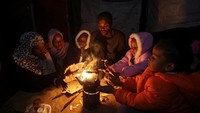 Obaid duduk bersama keluarganya di sekitar api unggun di perkemahan tenda mereka tempat ia menggali lubang bawah tanah untuk melindungi mereka dari serangan Israel.
