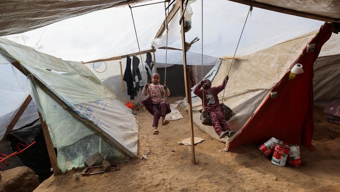 Displaced Palestinian man Tayseer Obaid sits with his family in an underground pit he dug at their tent encampment to protect them from Israeli strikes, in Deir Al-Balah, central Gaza Strip, January 6, 2025. REUTERS/Ramadan Abed     TPX IMAGES OF THE DAY