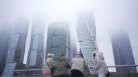 Orang-orang bersantai di jalan dengan latar belakang gedung pencakar langit di distrik bisnis Kota Moskow, Rusia, Selasa (7/1/2025).  