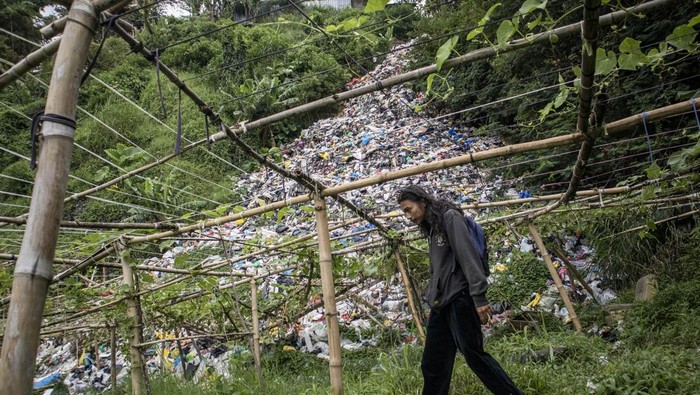 Tumpukan Sampah di TPS Ilegal Ini Bak Air Terjun Warga memperbaiki kayu penyangga tanaman di dekat tempat pembuangan sampah (TPS) ilegal di Gudangkahuripan, Lembang, Kabupaten Bandung Barat, Jawa Barat, Rabu (8/1/2025). Warga setempat mengeluhkan keberadaan TPS yang diduga tidak memiliki izin tersebut karena menimbulkan aroma tidak sedap dan mencemari lingkungan sekitar. ANTARA FOTO/Abdan Syakura/rwa.