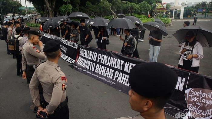 Sejumlah pegiat HAM berdiri tegak saat aksi Kamisan ke-846 di depan Istana Merdeka, Jakarta, Kamis (9/1/2025). Mereka memegang payung dengan tulisan tuntutan terkait kasus pelanggaran HAM. Selain itu, para peserta aksi mendesak pemerintah menghindari kebijakan ekonomi yang membebani masyarakat.