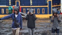 Warga menutup kepala mereka dengan kantong plastik agar tidak terkena air hujan.  