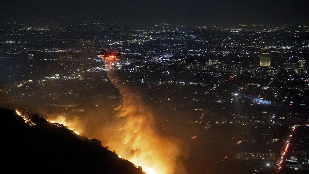 Helikopter menyemprotkan air ke lokasi kebakaran Sunset Fire di kawasan Hollywood Hills, Los Angeles, Rabu, 8 Januari 2025. (AP/Ethan Swope)