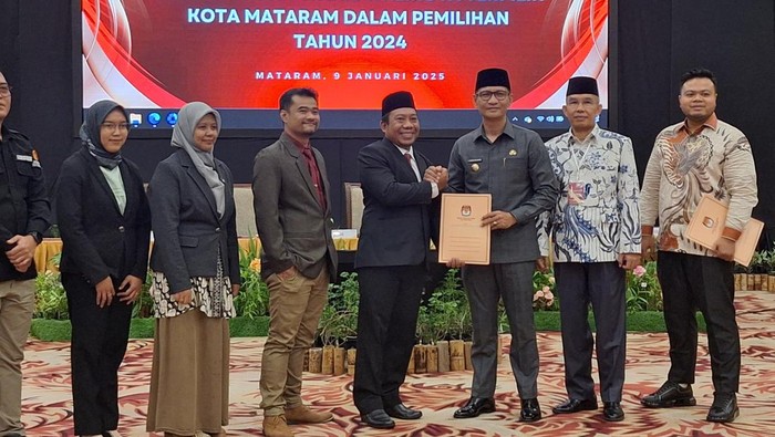 Ketua KPU Mataram, Edy Putrawan, menyerahkan hasil penetapan pemenang Pilwalkot 2024 kepada walkot terpilih, Mohan Roliskana, seusai rapat pleno di Lombok Raya Hotel, Kamis (9/1/2024). (Nathea Citra/detikBali)