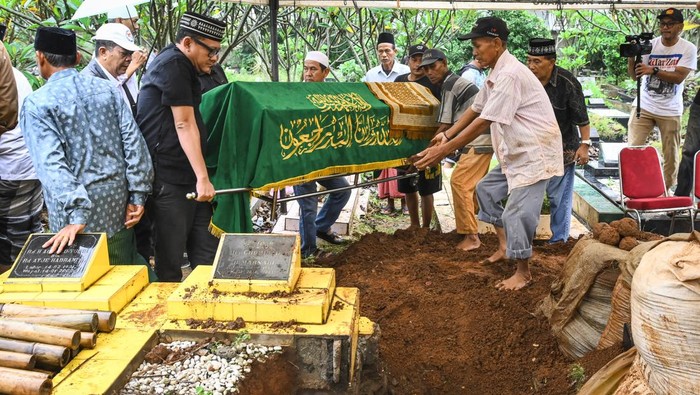 Istri pelawak sekaligus politikus Nurul Qomar, Siti Maryam (tengah) membawa bingkai foto dan berdoa saat pemakaman di TPU Carang Pulang, Pagedangan, Kabupaten Tangerang, Banten, Kamis (9/1/2025). Nurul Qomar meninggal dunia usai menjalani perawatan di RSUD Kabupaten Tangerang pada Rabu (8/1/2025). ANTARA FOTO/Sulthony Hasanuddin/foc.