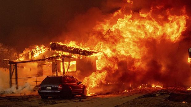 The Palisades Fire ravages a neighborhood amid high winds in the Pacific Palisades neighborhood of Los Angeles, Tuesday, Jan. 7, 2025. (AP Photo/Ethan Swope)