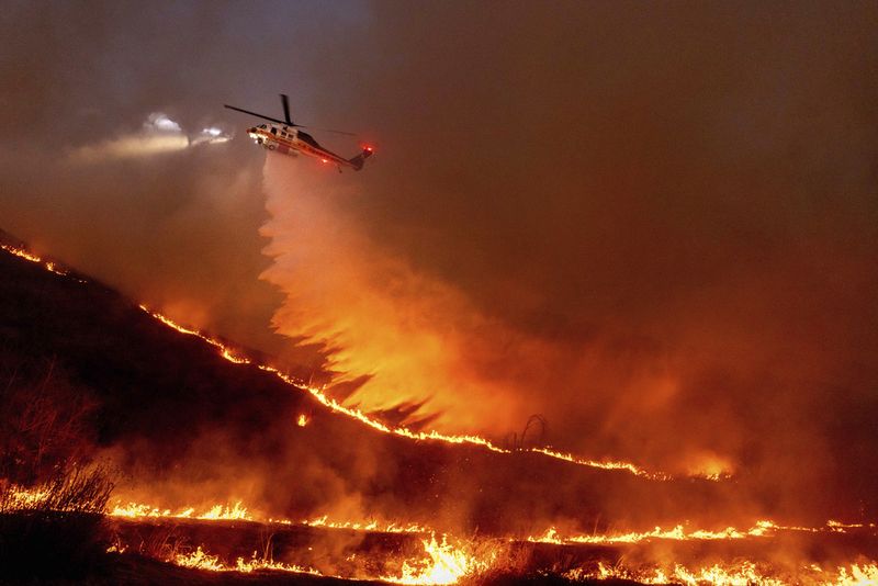 The Palisades Fire ravages a neighborhood amid high winds in the Pacific Palisades neighborhood of Los Angeles, Tuesday, Jan. 7, 2025. (AP Photo/Ethan Swope)