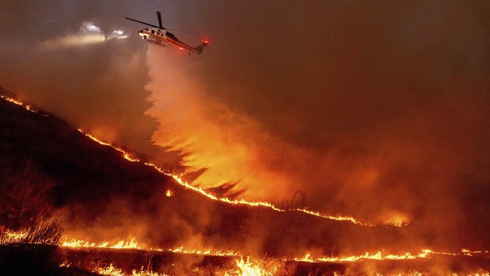 The Palisades Fire ravages a neighborhood amid high winds in the Pacific Palisades neighborhood of Los Angeles, Tuesday, Jan. 7, 2025. (AP Photo/Ethan Swope)