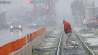 Warga berjalan di rel kereta api yang tertutup salju.  