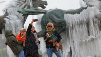 Orang-orang berswafoto di monumen Los Indomables saat salju turun, di Ciudad Juarez, Meksiko, Kamis (9/1) waktu setempat.  