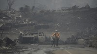 Seorang pria mengendarai sepedanya di antara reruntuhan yang ditinggalkan oleh Kebakaran hutan dahsyat di kawasan Pacific Palisades, Los Angeles, California, AS. AP/Damian Dovarganes