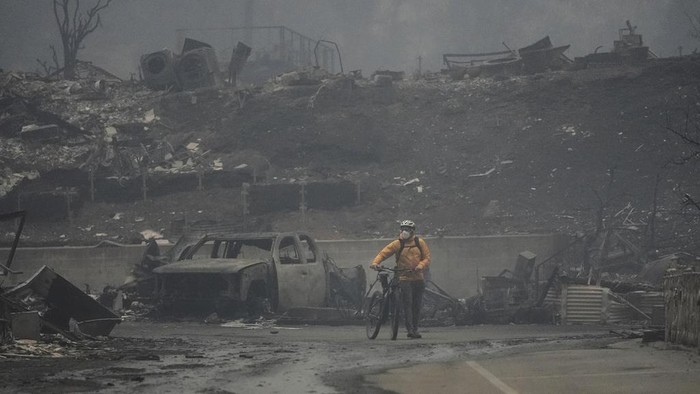 Potret Kehancuran Los Angeles Akibat Kebakaran Hutan A man walks his bike among the ruins left behind by the Palisades Fire in the Pacific Palisades neighborhood of Los Angeles, Wednesday, Jan. 8, 2025. (AP Photo/Damian Dovarganes)