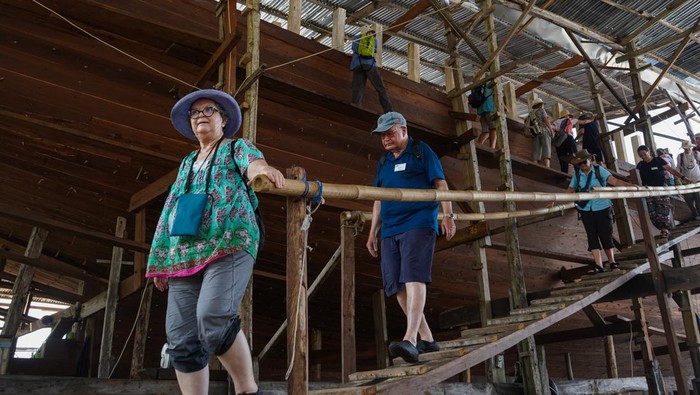 Wisatawan mancanegara menyaksikan proses pembuatan kapal Pinisi di Tanah Beru, Kabupaten Bulukumba, Sulawesi Selatan, Jumat (10/1/2025). Puluhan turis dari berbagai negara tersebut datang untuk mengenal lebih dekat warisan budaya maritim Indonesia yang telah diakui UNESCO sebagai warisan budaya takbenda, sekaligus menyaksikan langsung keahlian para pengrajin lokal dalam membangun kapal secara tradisional menggunakan pasak kayu. ANTARA FOTO/Hasrul Said/foc.