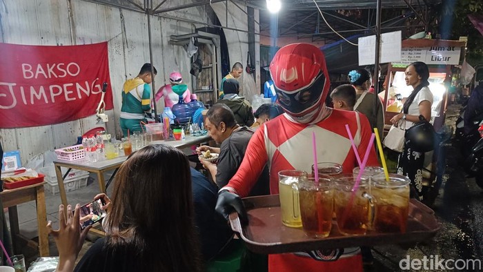 Para karyawan mengenakan kostum Power Rangers saat melayani pembeli di Bakso Jimpeng, Jalan Jenderal Soedirman, Purwokerto, Banyumas, Sabtu (11/1/2025) malam.