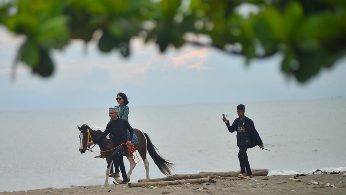 Santri memandu pengunjung yang menyewa jasa kuda wisata di Pantai Pasir Jambak, Padang, Sumatera Barat, Minggu (12/1/2025). Santri dari pondok pesantren Kanzul Ulum Padang itu menyewakan jasa berkuda dengan tarif Rp40 ribu per orang dan Rp10 ribu per orang untuk berfoto, dalam rangka menjalankan program kemandirian yang didukung Kementerian Agama dalam menunjang ekonomi pesantren meliputi inovasi perekonomian untuk para santri dan masyarakat sekitar. ANTARA FOTO/Iggoy el Fitra/nym.