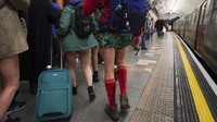 Orang-orang berjalan di sepanjang peron stasiun bawah tanah saat mereka mengikuti acara tahunan No Trousers Tube Ride di London, Minggu (12/1/2025).  