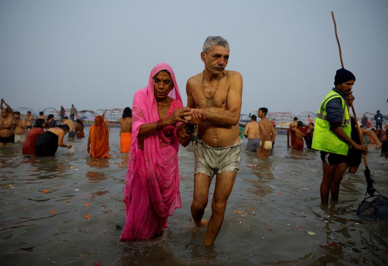 People leave the water after taking a holy dip at Sangam, the confluence of the Ganges and Yamuna rivers with the mythical, invisible Saraswati river, during the 