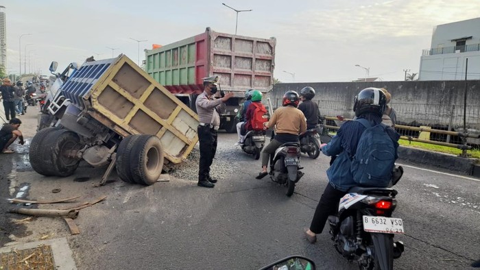 Truk muatan sirtu mengalami patah as di flyover Semanan hingga menimbulkan kemacetan, Senin (13/1/2025) pagi.