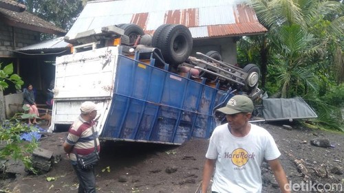 Truk pasir terbalik setelah menabrak rumah dan warung di Karangasem, Bali, Senin (13/1/2024).