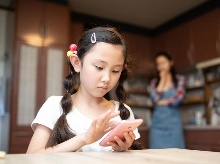 Daughter operating a smartphone and mother worried