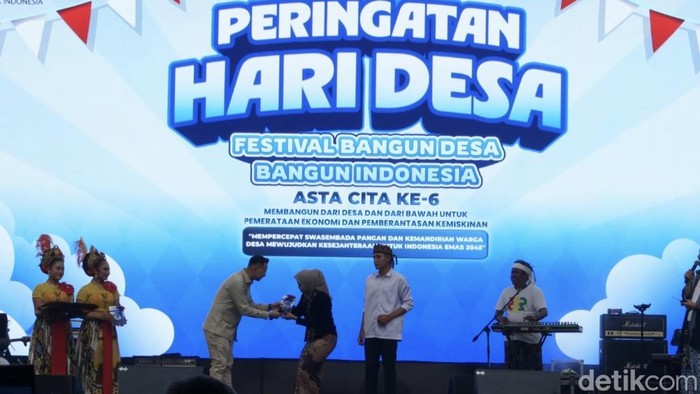 Raffi Ahmad memberikan buku panduan sebagai penanda lomba pemuda-pemudi pelopor desa di peringatan hari desa di Subang