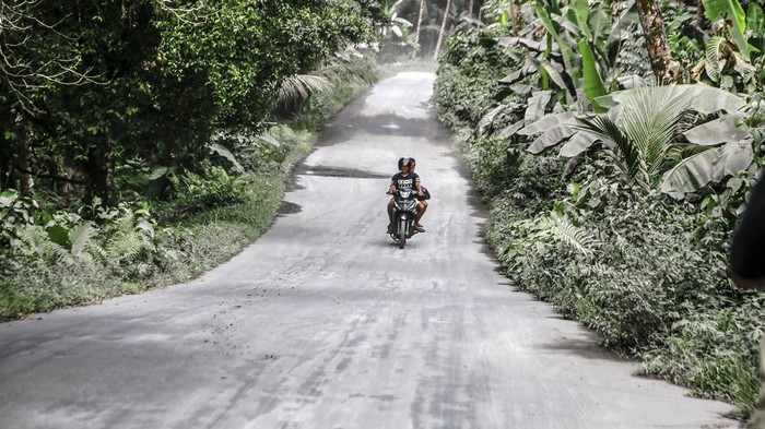 Pengendara sepeda motor melintas di jalan umum yang tertutup abu vulkanik dampak erupsi Gunung Ibu di Desa Tobaro, Kabupaten Halmahera Barat, Maluku Utara,Rabu (15/1/2025). Erupsi Gunung Ibu pada Rabu (15/1) pukul 07.11 WIT dengan semburan abu vulkanik setinggi 4.000 dari atas puncak menyebabkan sejumlah desa di Kecamatan Ibu Utara mengalami hujan abu, sementara gunung tersebut masih menunjukkan peningkatan aktivitas dan PVMBG menaikan status Gunung Ibu dari Siaga Level III menjadi Awas Level IV.