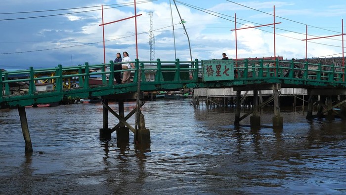 Dua warga menaiki perahu motor saat melewati barisan kapal penangkap ikan di Pelabuhan Sungai Kakap di Kabupaten Kubu Raya, Kalimantan Barat, Rabu (15/1/2025). Pelabuhan Sungai Kakap yang merupakan pusat pendaratan ikan dari kapal nelayan tradisional yang menjaring hasil laut di Natuna dan sekitarnya tersebut adalah salah satu destinasi unggulan wisata Desa Sungai Kakap. ANTARA FOTO/Jessica Wuysang/rwa.