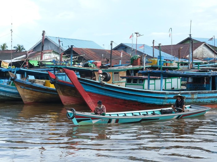 Dua warga menaiki perahu motor saat melewati barisan kapal penangkap ikan di Pelabuhan Sungai Kakap di Kabupaten Kubu Raya, Kalimantan Barat, Rabu (15/1/2025). Pelabuhan Sungai Kakap yang merupakan pusat pendaratan ikan dari kapal nelayan tradisional yang menjaring hasil laut di Natuna dan sekitarnya tersebut adalah salah satu destinasi unggulan wisata Desa Sungai Kakap. ANTARA FOTO/Jessica Wuysang/rwa.