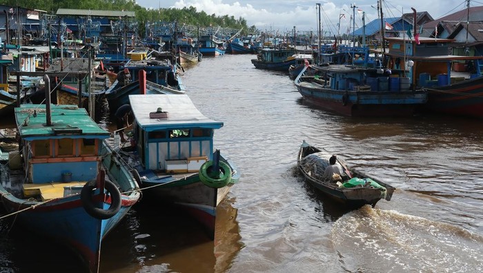 Dua warga menaiki perahu motor saat melewati barisan kapal penangkap ikan di Pelabuhan Sungai Kakap di Kabupaten Kubu Raya, Kalimantan Barat, Rabu (15/1/2025). Pelabuhan Sungai Kakap yang merupakan pusat pendaratan ikan dari kapal nelayan tradisional yang menjaring hasil laut di Natuna dan sekitarnya tersebut adalah salah satu destinasi unggulan wisata Desa Sungai Kakap. ANTARA FOTO/Jessica Wuysang/rwa.