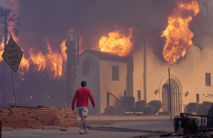 Seorang pria berjalan di depan Gereja Komunitas Altadena yang terbakar, Rabu, 8 Januari 2025, di pusat kota Altadena, Pasadena, California.