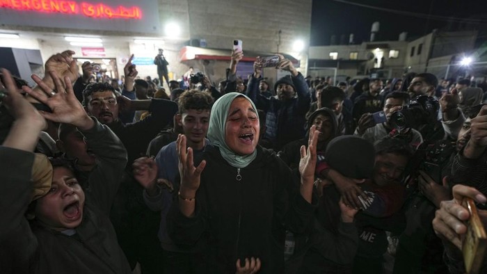 Palestinians watch TV as they await the imminent announcement of a ceasefire deal between Hamas and Israel in Khan Younis, central Gaza Strip, Wednesday, Jan. 15, 2025.(AP Photo/(AP Photo/Jehad Alshrafi)