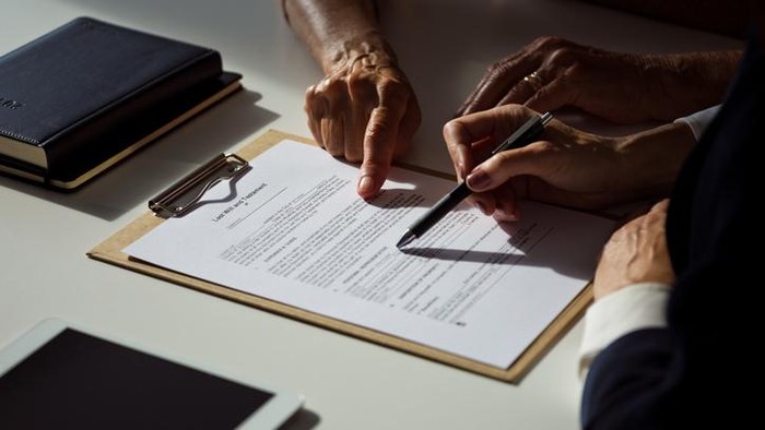 Female lawyer explaining the will to senior woman. Close up of hands, unrecognizable people.