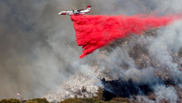 FILE PHOTO: A plane makes a drop as smoke billows from the Palisades Fire at the Mandeville Canyon, in Los Angeles, California, U.S., January 11, 2025.  REUTERS/Shannon Stapleton/File Photo