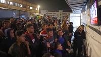 Anak-anak kecil, beberapa tampak bingung oleh keributan itu, berkumpul di luar rumah sakit juga, berdesakan di antara orang dewasa dan menonton saat mereka memberikan wawancara kepada media yang menunggu. Foto: Bashar Taleb/AFP
