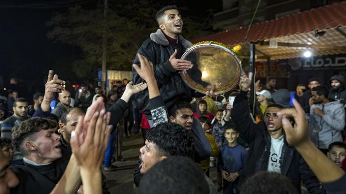 Palestinians celebrate the announcement of a ceasefire deal between Hamas and Israel in Deir al-Balah, central Gaza Strip, Wednesday, Jan. 15, 2025. (AP Photo/Abdel Kareem Hana)