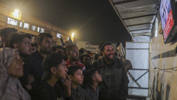 Palestinians watch TV as they await the imminent announcement of a ceasefire deal between Hamas and Israel in Khan Younis, central Gaza Strip, Wednesday, Jan. 15, 2025.(AP Photo/(AP Photo/Jehad Alshrafi)