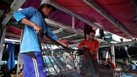 Para nelayan mengisi waktu dengan memperbaiki jaring.