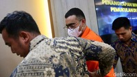 Tampak pelaku digiring dengan memakai baju tahanan. 