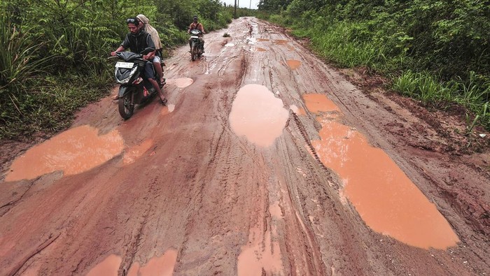 Pengendara melintasi jalan rusak di Desa Ladang Panjang, Muaro Jambi, Jambi, Jumat (17/1/2025). Jalan tanah yang menjadi satu-satunya akses warga setempat ke desa sekitar itu kondisinya berlubang dan licin setiap diguyur hujan sehingga membahayakan pengendara. ANTARA FOTO/Wahdi Septiawan/nym.