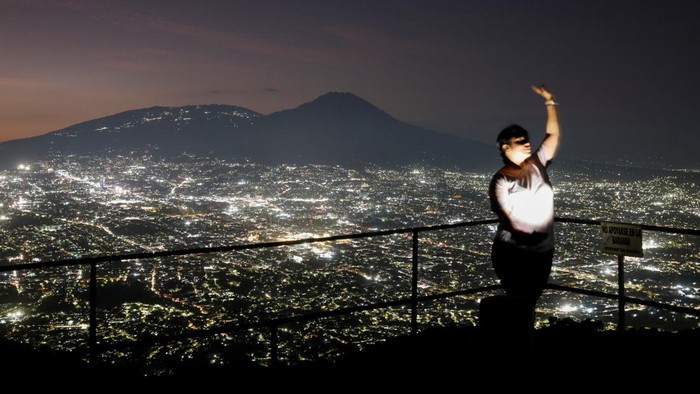 A woman makes a video with the view of the city of San Salvador from the San Antonio Amatepec farm lookout point, in Soyapango, El Salvador, January 16, 2025. REUTERS/Jose Cabezas