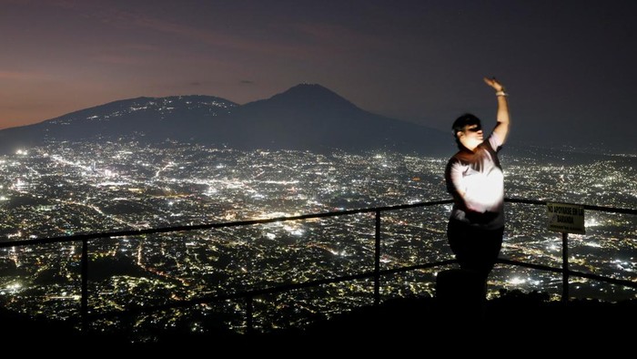 Menikmati Kelap-kelip Panorama Kota Soyapango El Salvador A woman makes a video with the view of the city of San Salvador from the San Antonio Amatepec farm lookout point, in Soyapango, El Salvador, January 16, 2025. REUTERS/Jose Cabezas